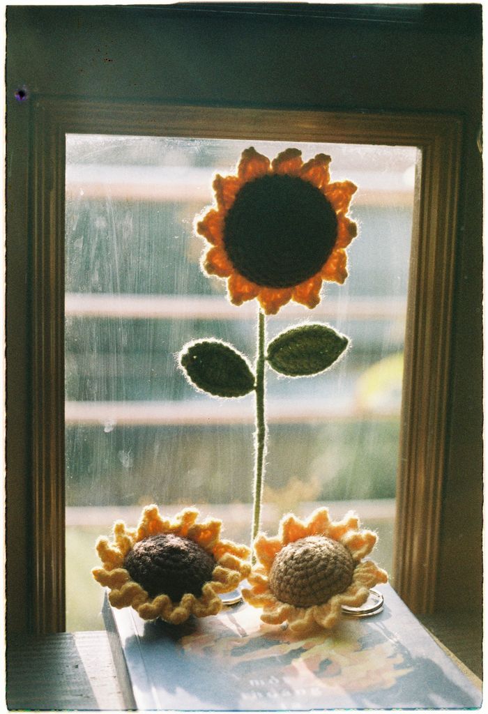 Handcrafted crochet sunflowers placed by a sunlit window, capturing a cozy vibe.