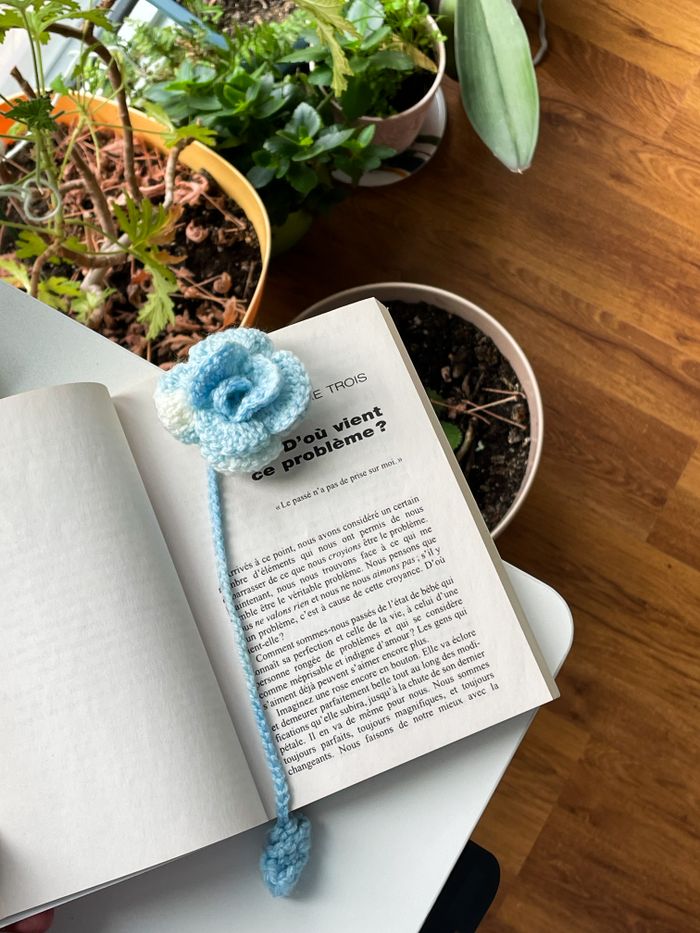 Open book with crocheted bookmark and plants in home setting, creating a relaxing atmosphere.