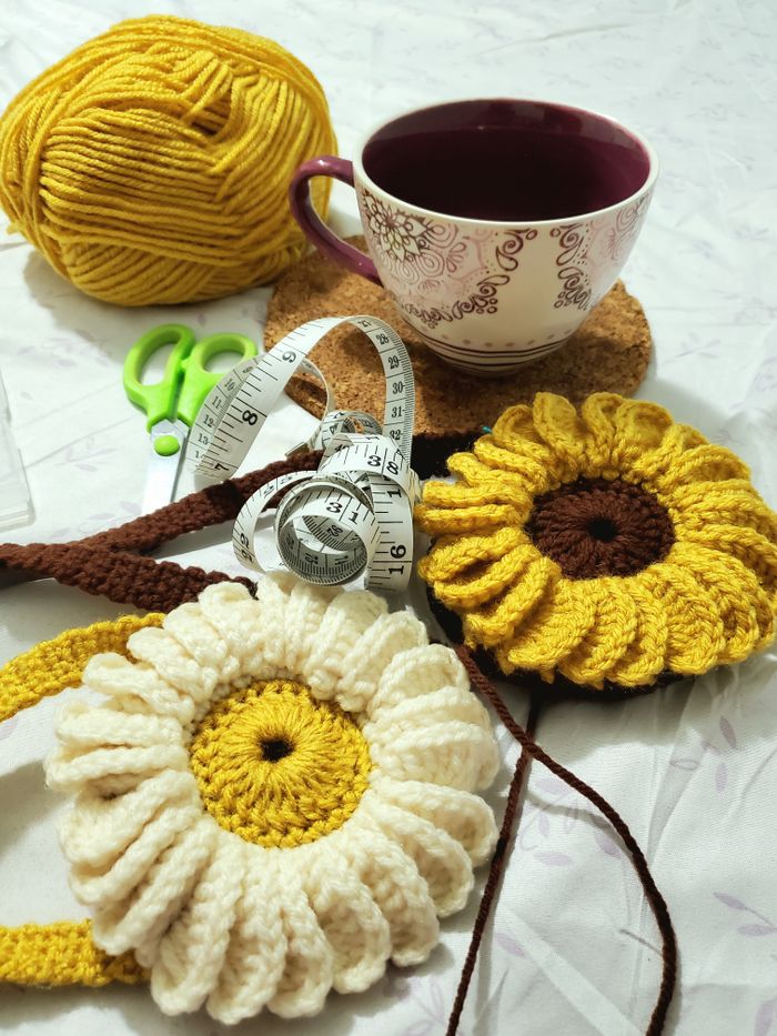 A cozy scene with knitting yarn, crochet flowers, and a warm cup of tea on a crafting table.